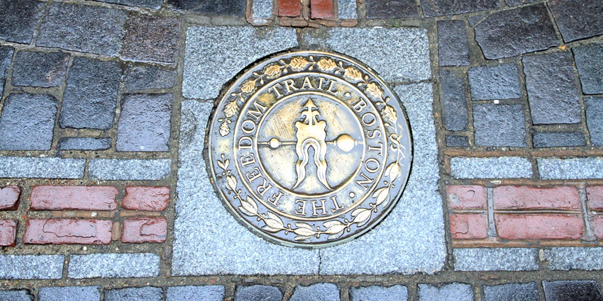 Freedom trail path next to the red building, Faneuil Hall with people and children walking