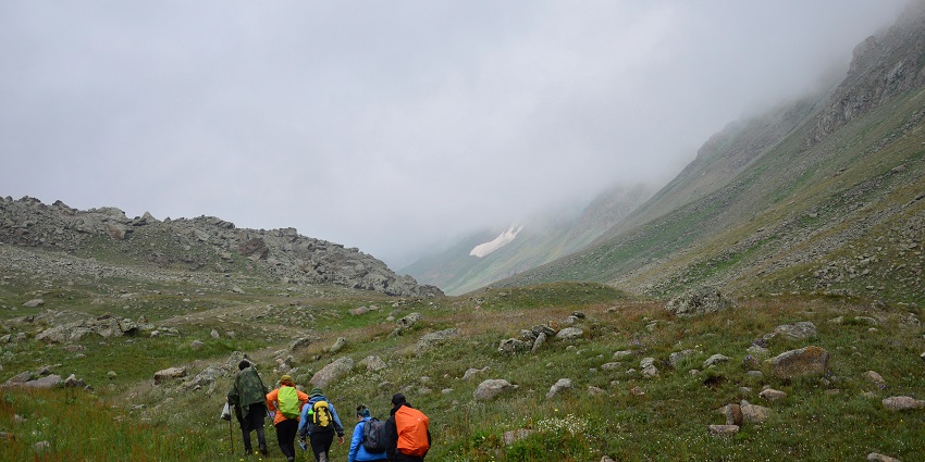 A view of a woman trekking to Ghatandevi Temple, offering scenic views of the lush landscape.