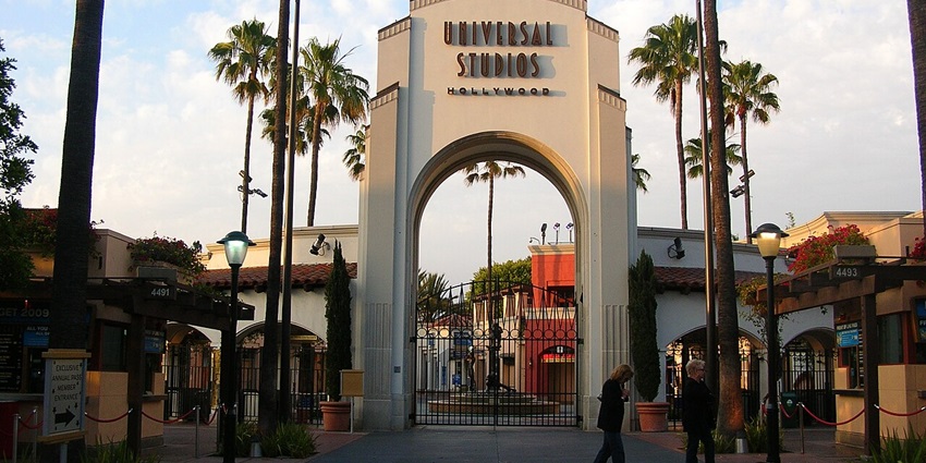 The entrance gate of Universal Studio Hollywood with palm trees and people walking