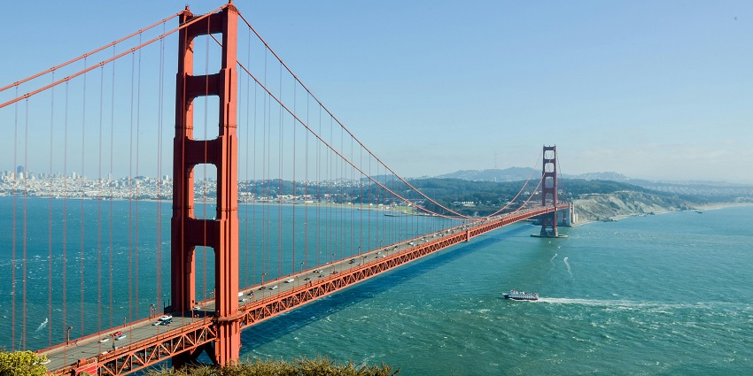 An aerial view of the San Francisco Golden Gate Bridge across which there is a city.