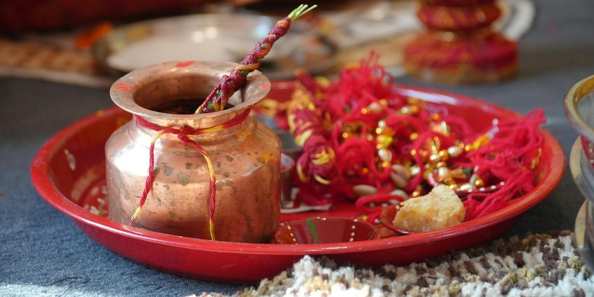 A detailed view of a pooja thali decorated with flowers, and other hindu ritual things