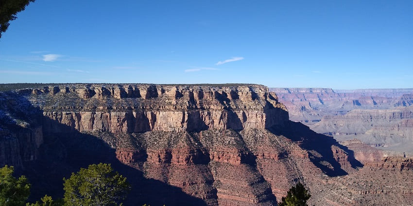 Golden sunset over the Grand Canyon, casting warm light on the canyon's rugged landscape.