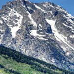 An image of Teton Range with snow-capped peaks and Willow Flats' green meadows.