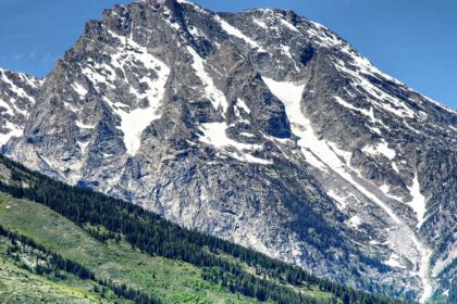 An image of Teton Range with snow-capped peaks and Willow Flats' green meadows.