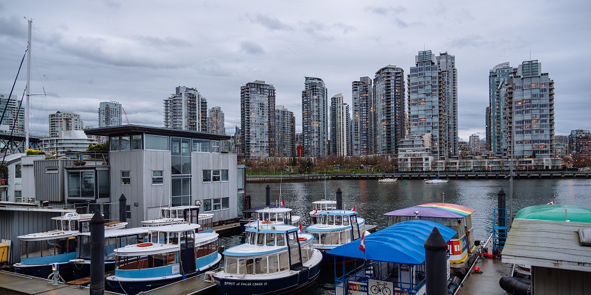 Boats parked in Granville Island at the lake near the lake deck with buildings in the backdrop