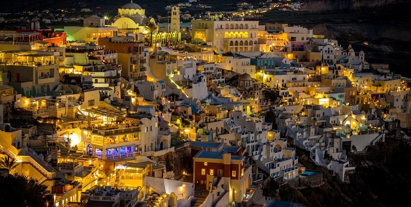 Greece at night with well-lit restaurants, clubs rooftop bars and a distant coastline