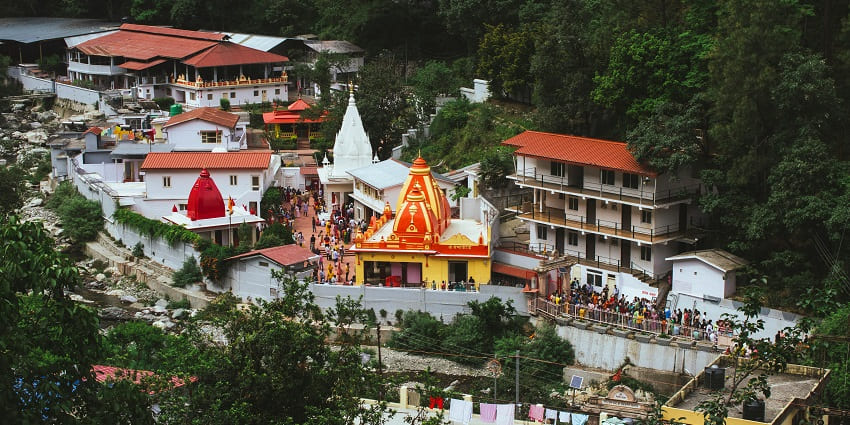 An image of the entrance of Hanumat Dham temple surrounded by lush greenery.