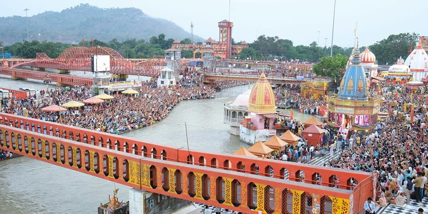 An aerial view of Haridwar featuring majestic temples, azure waters, and crowds of people.