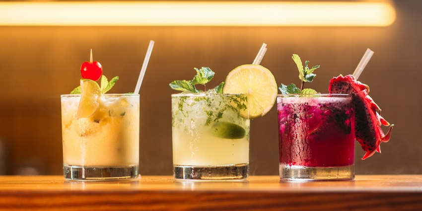 Image of 3 glass of drink with colourful design lined up on a table