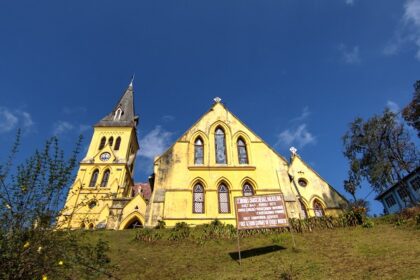 An image of the Darjeeling with equally stunning multi-hued buildings and mountains behind them.