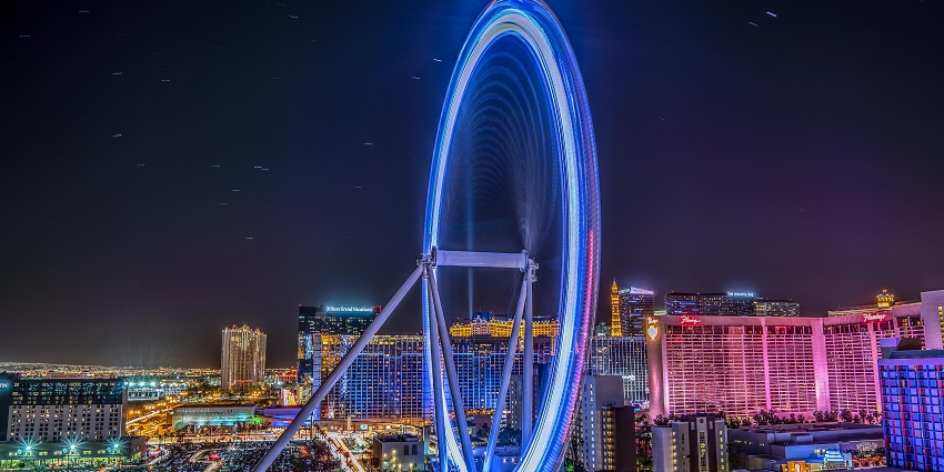High roller observation wheel with a shopping complex, fountain and people visiting