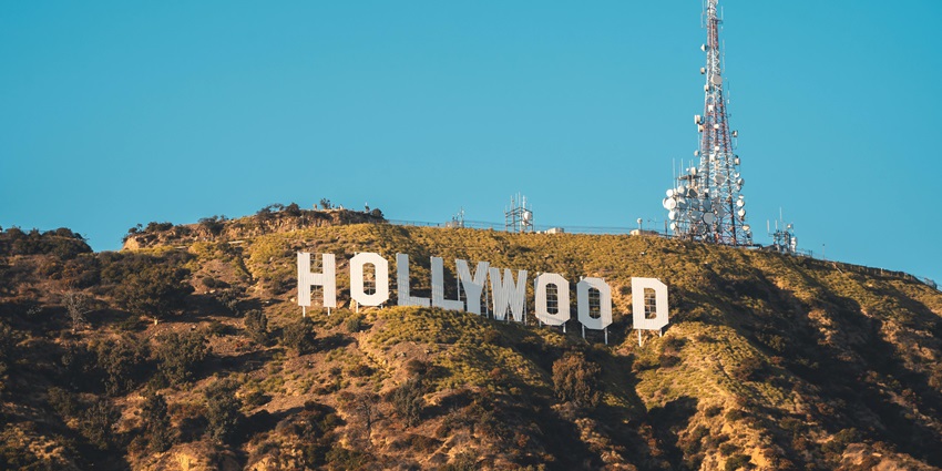 Sunlight hitting the Hollywood sign on a mountain with multiple network towers on top.