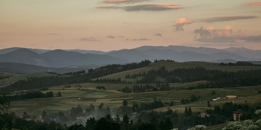 Greeny Carpathian mountains in the evening with small houses, green trees and mountains