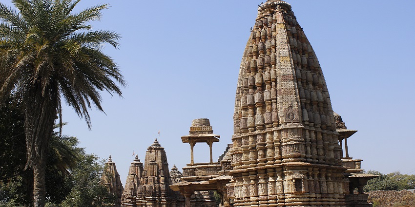 An image of a peaceful Hindu temple, with tall pillars and a clear blue sky in the background.