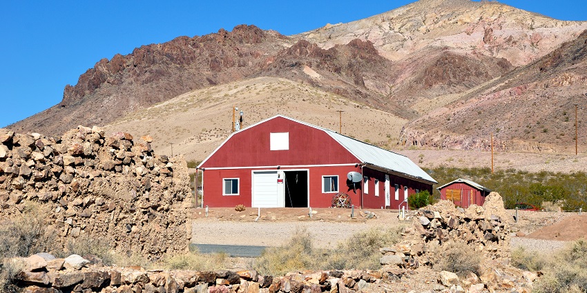 A vibrant red barn stands against a clear sky, surrounded by grassy fields at Bullfrog