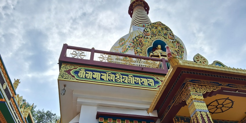 The top of the Buddhist Salugara Monastery structure surrounded by lush greenery.