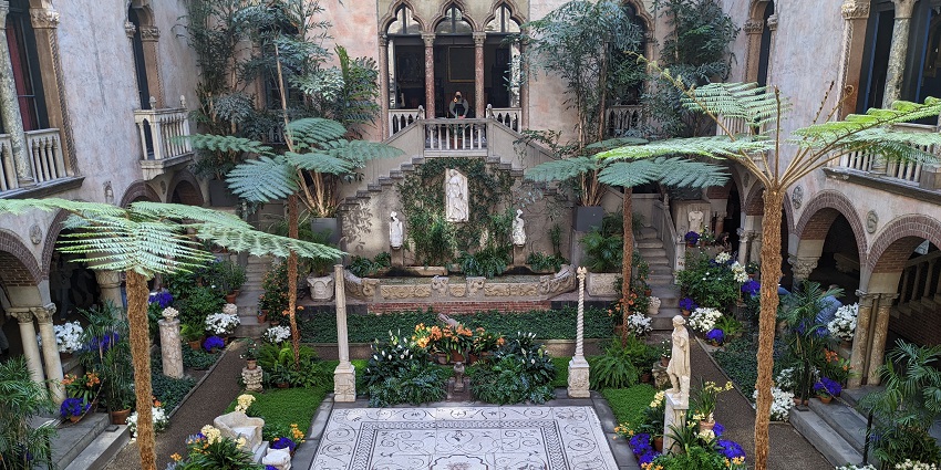 View of the courtyard of the Isabella Stewart Gardner Museum showing tiles, statues, plants and trees