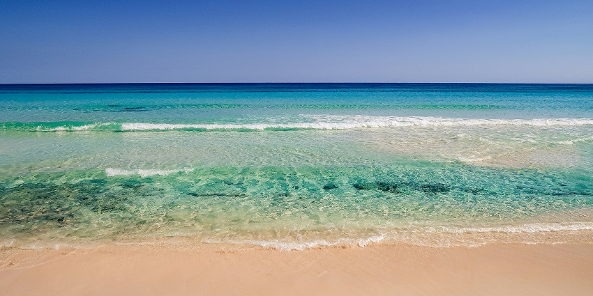 An image of sunset, reflecting golden hues on the water at one of Mexico beaches.