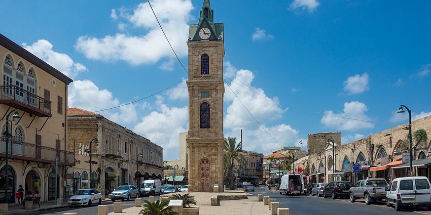 A picture of a city square in Jaffa with a clock tower in the middle of the street