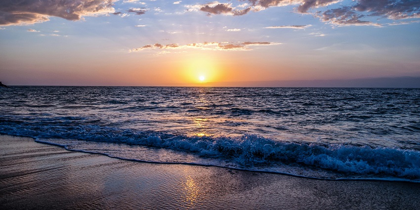 A picture of a beach amidst a serene sunset with golden hues
