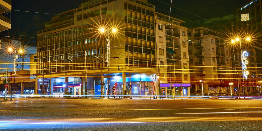 Empty roads of Kifisia Avenue with bright street lights, buildings and closed shops
