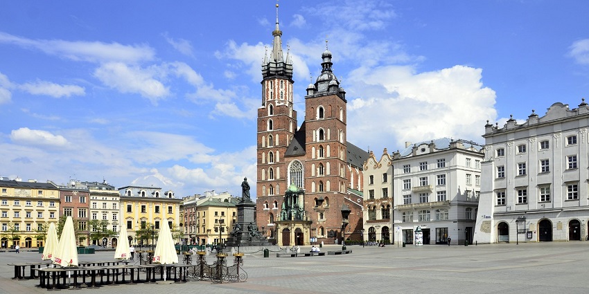 Empty old town market square in Kraków with vibrant buildings and a statue in the middle