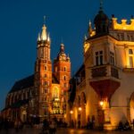 St Mary’s Basilica at night with well-lit buildings and people exploring around