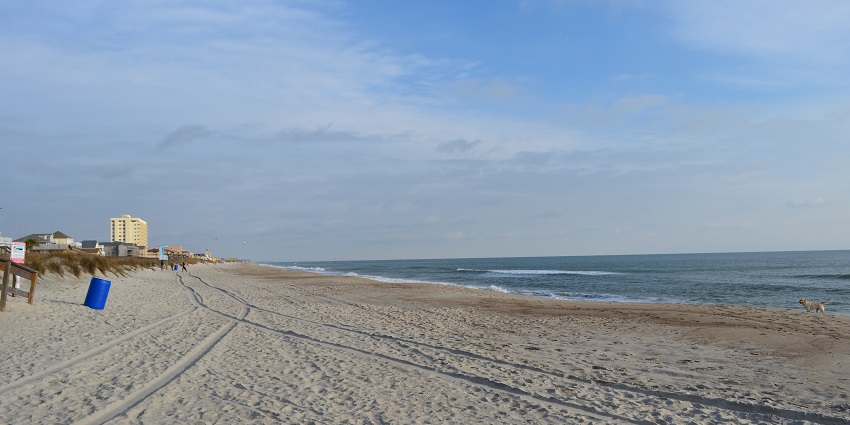 Kure Beach in North Carolina with a wooden pier extending over calm ocean waves.