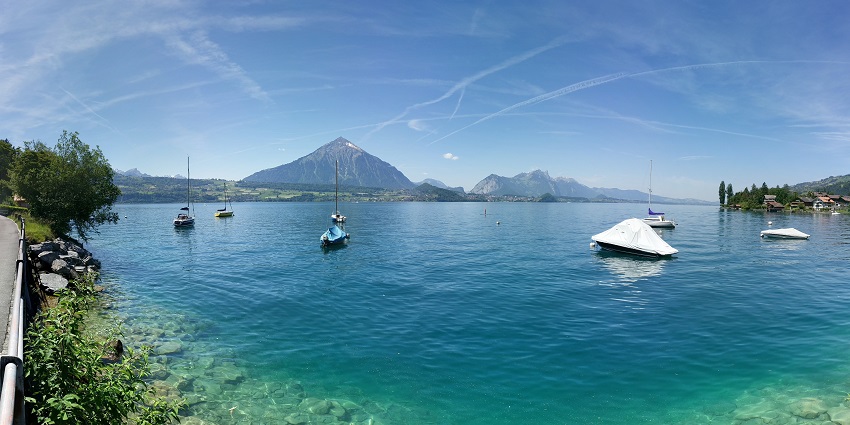 Serene Swiss Lake is surrounded by mountains, perfect for boating.
