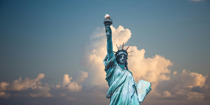 An aerial view of an Island showcasing the Statue of Lady Liberty in the middle of it.
