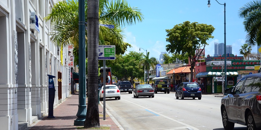 Streets lined with trees and colourful shops, busy with cars in Little Havana in Miami.
