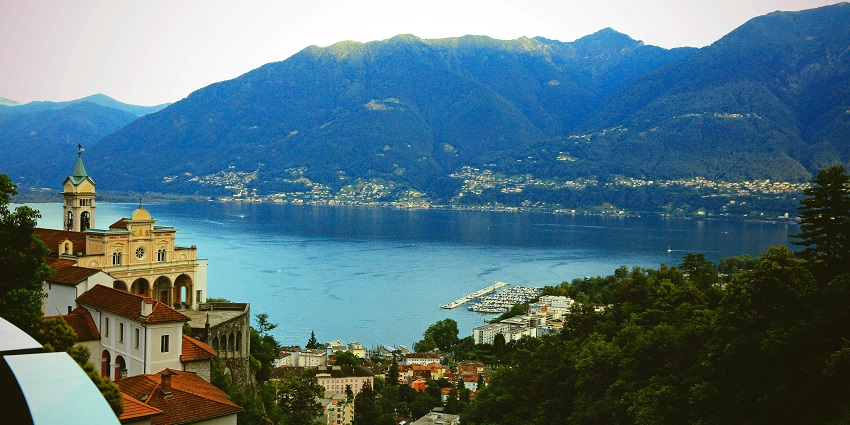Some people are enjoying in the shallow waters at Locarno Beach, with a mountain view.