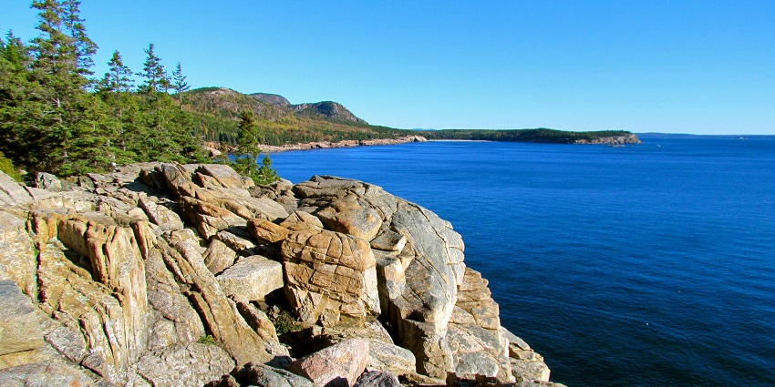 A scenic view of the rugged coastline of Acadia National Park with rocky cliffs.