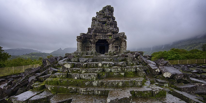 A panoramic view of the trek of Anjaneri Fort along a hiking trail with rolling hills.