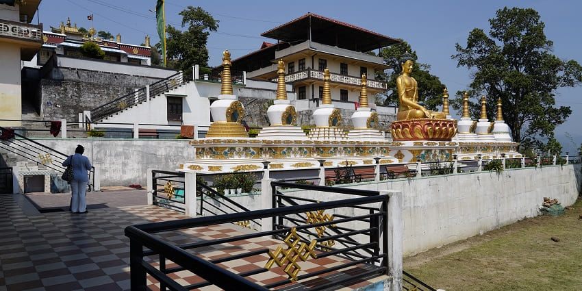 A picture of Geden Tharpa Choling Monastery, highlighting its vibrant red and yellow facade.