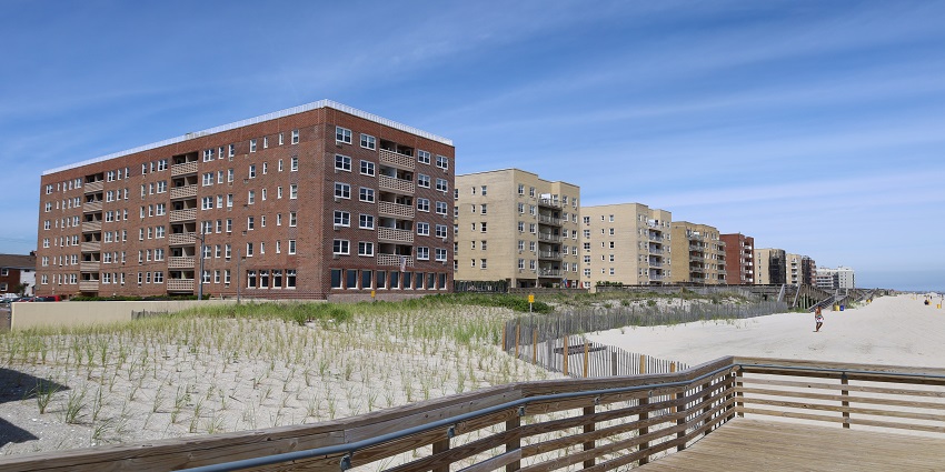 A row of brick and beige apartment buildings with balconies, situated on Long Beach