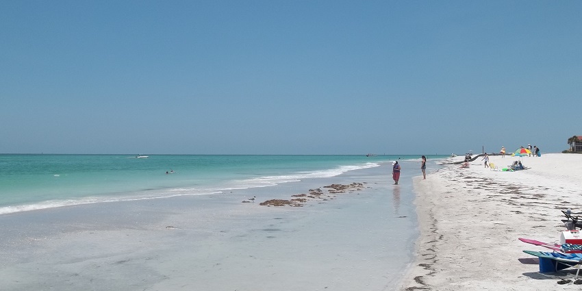 An image of a beach scene on Longboat Key, Florida, with calm waves and sandy shoreline views