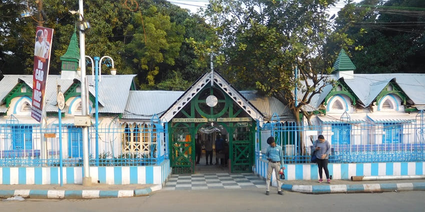 A picture of the entrance of a cemetery in Kolkata with blue walls and English architecture