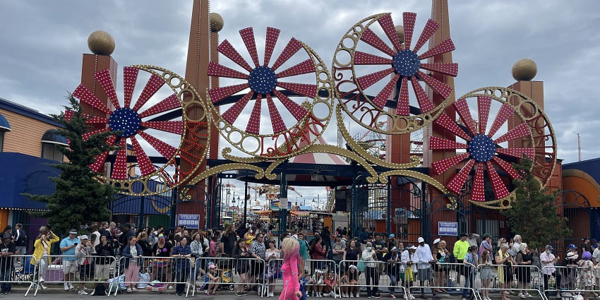 A view of a crowd enjoying a beautiful day in an amusement park in NYC.