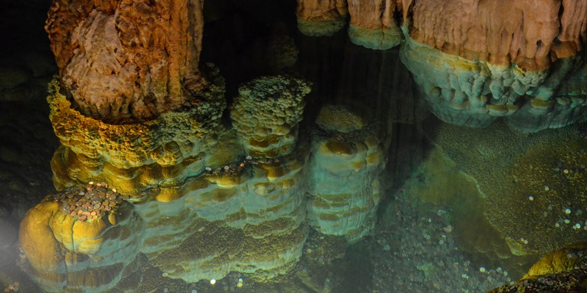 A picture of the intriguing cave system in Virginia with shallow water and a floor filled with coins