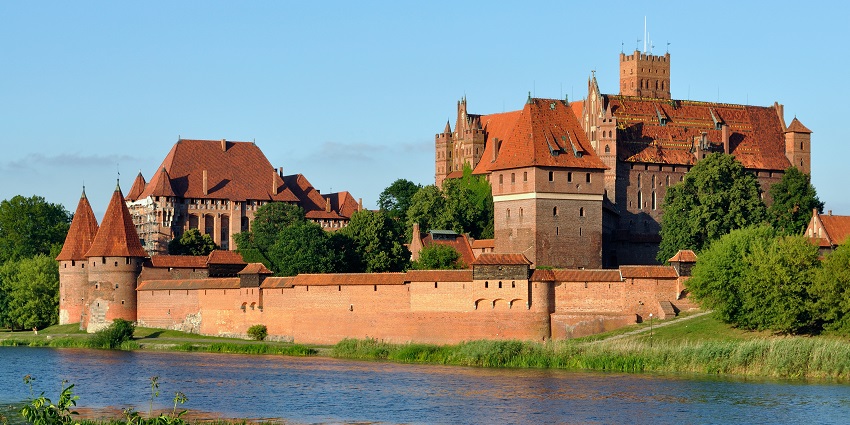 Malbork Castle with traditional Gothic architecture, red brick roofs and a river