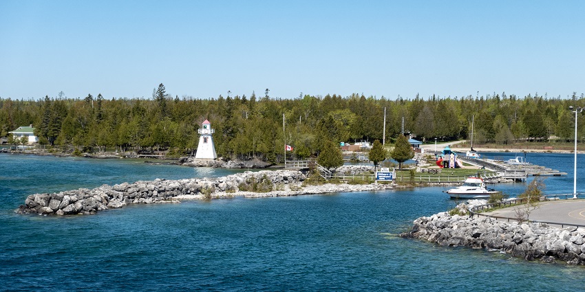 A lighthouse can be seen on a trail adjacent to a tranquil lake on Manitoulin Island.