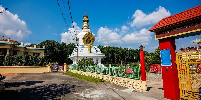 Image of Mindrolling Monastery surrounded by lush greenery under clear blue sky