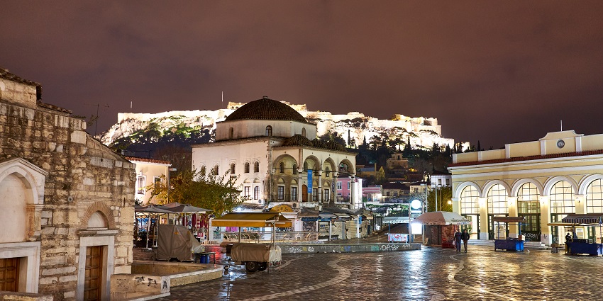 Monastiraki Square with local eateries, people visiting and illuminated buildings