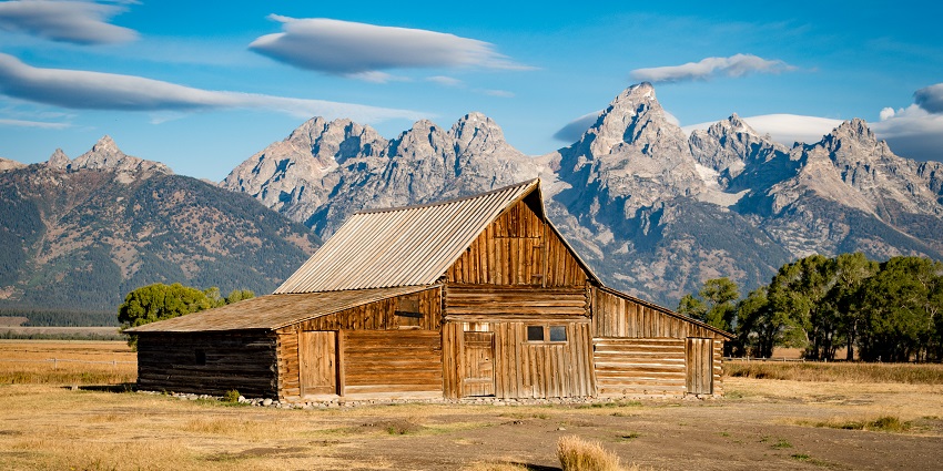 An image of Mormon Row Historic District with iconic barns and the stunning Teton Range.