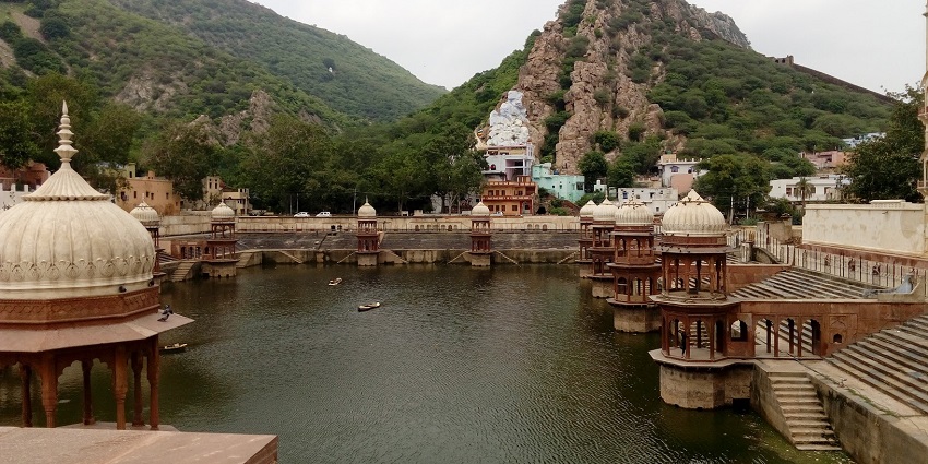 An image of Moti Jheel with structures surrounding it on one side of the view there is a hill