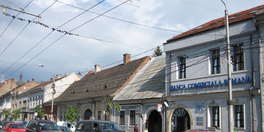 Street in Cluj-Napoca with a person walking on sidewalks and cars parked next to it.