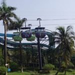 A picture of a water park in Kolkata with pine trees all around and an adventurous ride