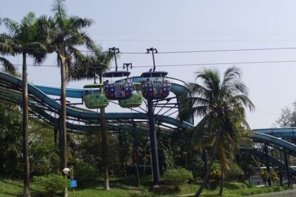 A picture of a water park in Kolkata with pine trees all around and an adventurous ride