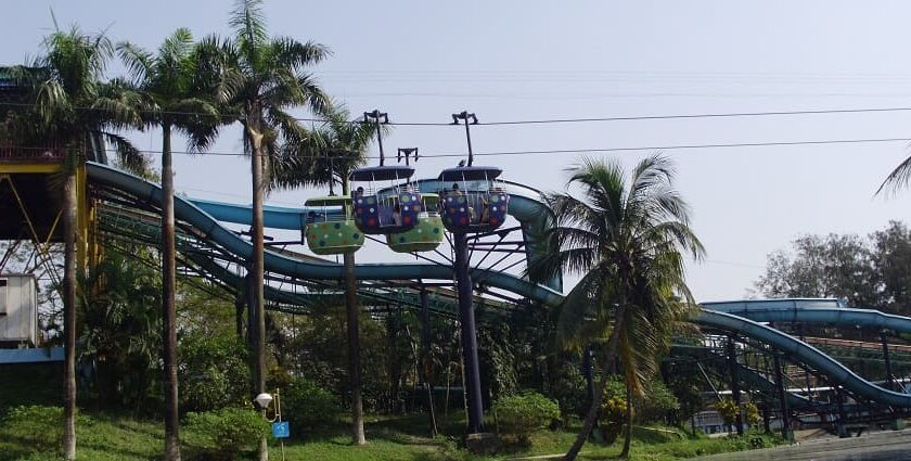 A picture of a water park in Kolkata with pine trees all around and an adventurous ride